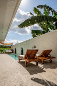 deux chaises longues en bois assises à côté d'une piscine dans l'établissement Spacious Design Villa 3bd, à Canggu