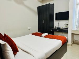 a bedroom with a large bed with a tv on it at Orange Corner Hotel, MONTHLY STAY AVAILABLE in Yelahanka
