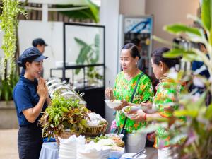 un gruppo di donne che si trovano intorno a un tavolo con cibo di Grand Yard La Residence a Siem Reap