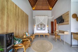 a living room with a bed and chairs and a television at Kulta Villa Bali in Munggu