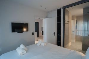 een slaapkamer met een wit bed en een tv aan de muur bij ID Residences 203 in Volos
