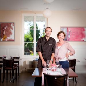 a man and a woman standing in a room with wine glasses at Auberge de la Gare in Grandvaux
