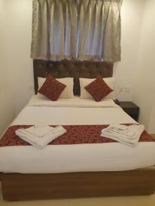 a bedroom with a bed with white sheets and pillows at Earth Inn in Chennai
