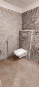 a bathroom with a toilet in a brick wall at Earth Inn in Chennai