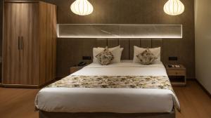 a bedroom with a large white bed with two pillows at The Cindrella Hotel in Siliguri