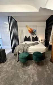 a bedroom with a large bed with two green chairs at Modern studio apartment in West Kensington in London