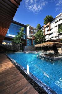 a swimming pool with chairs and a straw umbrella at Richmann Resort Hotel Hatyai in Ban Kohong