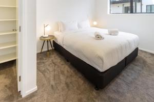 een slaapkamer met een groot wit bed en een tafel bij Sun soaked Central Townhouse 2 bed 2 bath in Christchurch