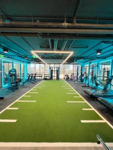 a gym with a green floor with benches and machines at 9D City & 9D Express Hotel in Udon Thani