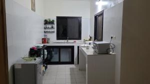 a white kitchen with a sink and a microwave at Lowéne in Guediawaye