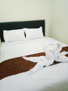 uma cama com lençóis brancos e almofadas brancas em De Plaza Hotel em Surabaya