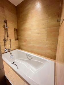 Una gran bañera blanca en una habitación con paredes de madera. en 9D City & 9D Express Hotel, en Udon Thani