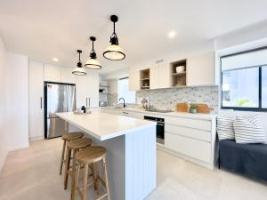 a kitchen with white cabinets and a large island with stools at Noosa Pacific Resort in Noosaville