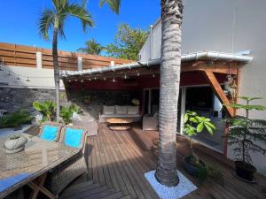 a wooden deck with chairs and a palm tree at Kaz Ti'Chouka, centre St-Leu, 40 m du lagon in Saint-Leu
