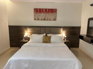 a bedroom with a large white bed with two night stands at استديو أنيق بدخول ذاتي in Al Kharj