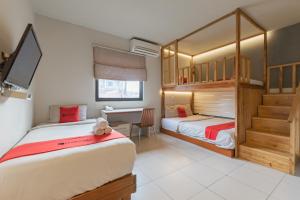 2 Betten in einem Zimmer mit einem Schreibtisch und einem Schreibtisch in der Unterkunft RedDoorz Plus near Asia Afrika 3 in Bandung