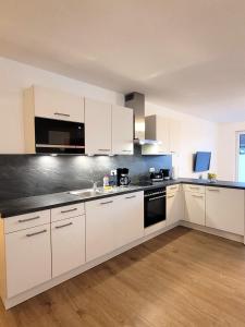 eine Küche mit weißen Schränken und einer schwarzen Arbeitsplatte in der Unterkunft Winterberg Appartement 21126 in Winterberg