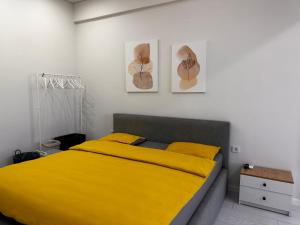 a bedroom with a yellow bed with two pictures on the wall at Comfortable Apartment located in downtown Bishkek in Bishkek