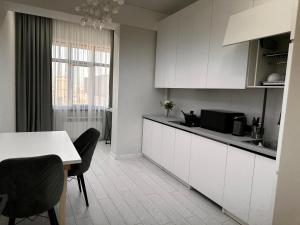a kitchen with white cabinets and a table and chairs at Comfortable Apartment located in downtown Bishkek in Bishkek