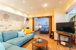 een woonkamer met een blauwe bank en een flatscreen-tv bij Lito's Central Gem - Cozy Dream Getaway in Kalamata