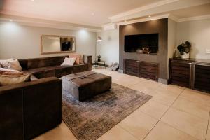 a large living room with a couch and a tv at Spacious home with pool 200M from beach in Cape Town