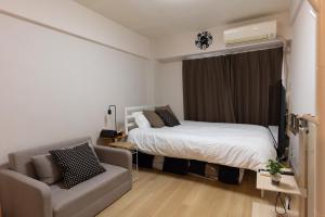 um pequeno quarto com uma cama e um sofá em gaojin 第2高津グローリーハイツ em Osaka