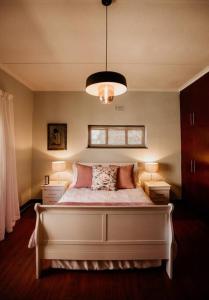 a bedroom with a large white bed with two lamps at Spacious home with pool 200M from beach in Cape Town