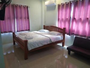 um quarto com uma cama de madeira e cortinas cor-de-rosa em โรงแรมพรถวิล ศรีสะเกษ Sisaket PonTaWin Budget Inn em Si Sa Ket