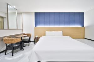 1 dormitorio con 1 cama, mesa y sillas en Calm Rest Hotel Busan Sasang en Busan