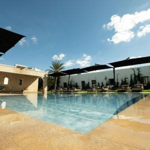 a swimming pool with chairs and umbrellas at Cavanna Lodge in Essaouira