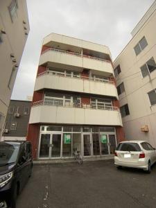 a tall building with cars parked in front of it at 新三条Home 402 in Asahikawa