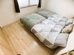 un letto non preparato in una camera con pavimento in legno di 新三条Home 402 a Asahikawa