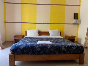 um quarto com uma cama com riscas amarelas e brancas em Residence Hotel La Marsu em Cap Skirring