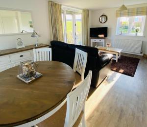a living room with a table and a couch at Pearl & Spice Hideaways - 2 two bedroom cottages nearby - Part of the The Bay Filey Holiday Village with pool, gym and direct beach access, pub, restaurant, tennis and meadows walks in Reighton