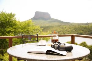 a table with a book and a camera and a bottle at Entabeni Mountain Lodges in Golders Green