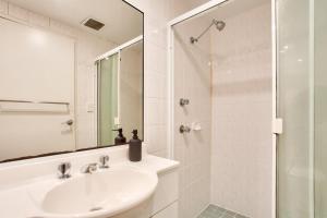 a white bathroom with a sink and a shower at Cozy 2 Bedroom Apartment Surry Hills in Sydney