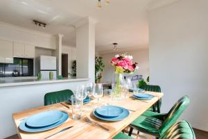 a dining room with a wooden table and green chairs at Cozy 2 Bedroom Apartment Surry Hills in Sydney