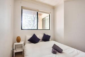 a bedroom with a bed with blue pillows and a window at Cozy 2 Bedroom Apartment Surry Hills in Sydney