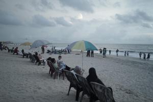 een groep mensen die onder parasols op het strand zitten bij Marari Red Angel in Mararikulam