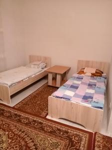 two beds and a table in a room at Азия Hotel in Taraz