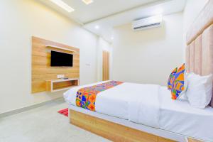 a white bedroom with a bed and a tv at FabHotel Bohra International in Jaipur