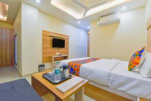 a bedroom with a bed and a table and a tv at FabHotel Bohra International in Jaipur