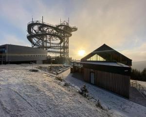 un edificio en una colina nevada con el sol en el fondo en Apartmán U Pošty Králíky, en Králíky