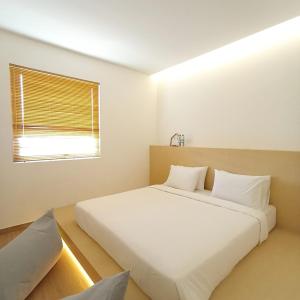 um quarto com uma grande cama branca e uma janela em ManukabyHavis Boutique Hotel em Nagoya