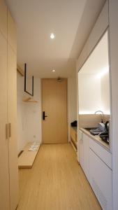 a kitchen with white cabinets and a hallway with a door at ManukabyHavis Boutique Hotel in Nagoya