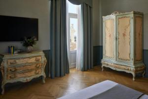 a bedroom with a dresser and a large window at Hotel Villa Del Sogno in Gardone Riviera