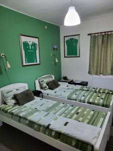 2 camas en una habitación con paredes verdes en Vila Mala Evropa en Leskovac