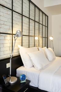 Cama con almohadas blancas y mesa con lámpara en Magnova Studios, en Estambul