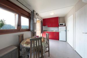 スマイアにあるCamping & Bungalows Zumaiaのキッチン(赤いキャビネット、テーブル、椅子付)