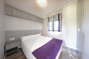 Un dormitorio con una cama con una manta morada. en Camping & Bungalows Zumaia, en Zumaia